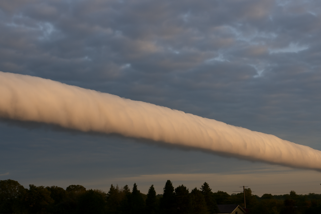 سحابة طويلة أسطوانية الشكل تمتد أفقياً فوق الأفق في ظاهرة الغيوم المتدحرجة النادرة.